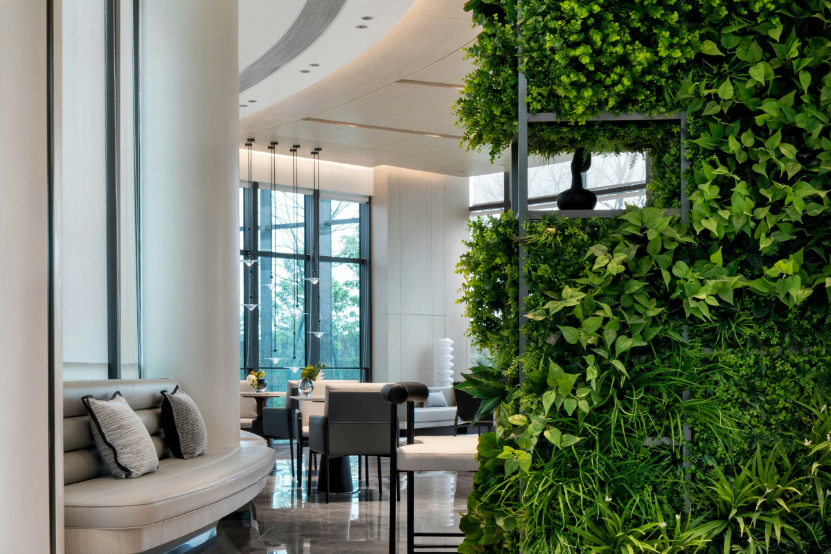 Giardino verticale indoor con piante verdi rigogliose su parete modulare, in ambiente moderno e luminoso.
